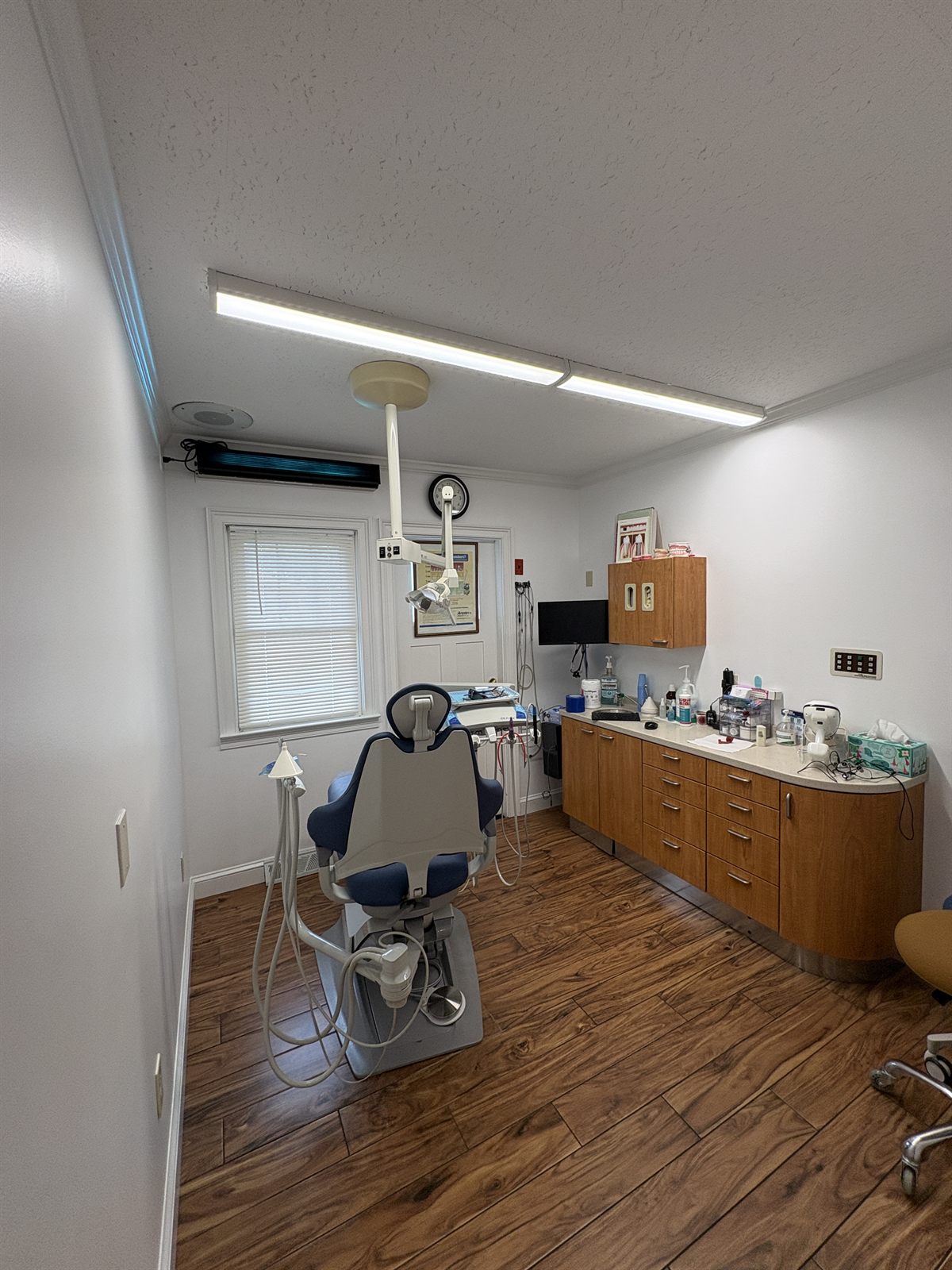 Spacious treatment room at Stratford Dental Care with a dental chair, wood cabinetry, and natural light